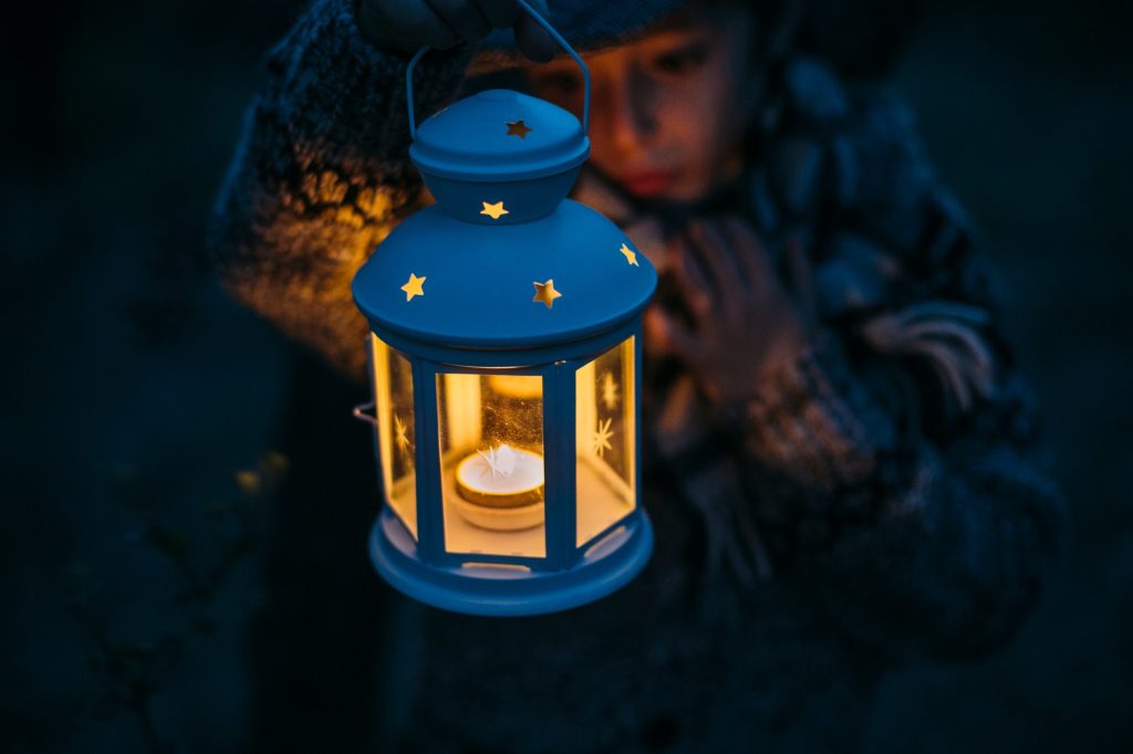 Italy, Grosseto, boy looking at a lighted Christmas lantern by night